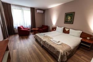 a hotel room with a bed and two chairs at Philippopolis Hotel in Plovdiv +59 photos