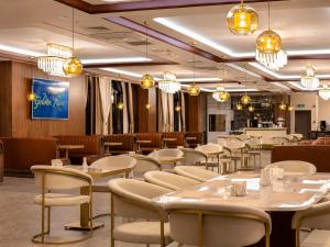 a restaurant with white tables and chairs and chandeliers at Golden River Hotel By Continent in Arnavutköy