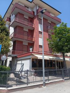 a tall red building with a fence in front of it at HOTEL ROSSINI in Rimini