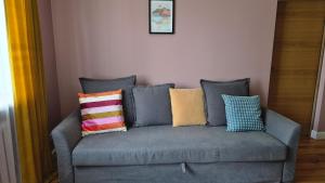 a gray couch with colorful pillows on it at Tulasi homestay in Madona