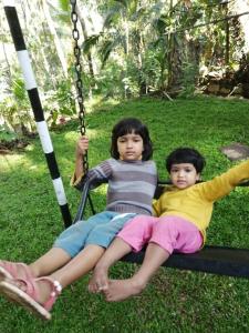 two young children sitting on a swing at Miracle holiday homestay in Demodera