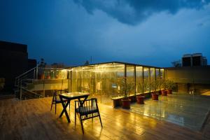 a glass building with a table and chairs on a deck at Barsana Hotel & Resorts in Jaipur