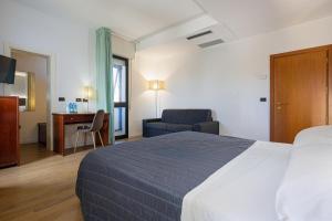 a hotel room with a bed and a chair and a desk at Hotel Sirena & Cucina in Cesenatico