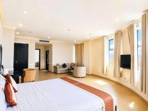 a bedroom with a large bed and a living room at Quê Tôi Hotel in Soc Trang
