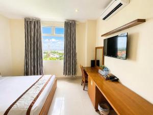 a hotel room with a bed and a desk and a television at Quê Tôi Hotel in Soc Trang