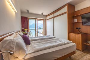 a bedroom with a bed with a view of a balcony at Ambienthotel Spiaggia in Malcesine +90 photos