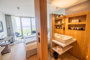 a bathroom with a sink and a bedroom with a view at Hotel Misan in Norderney +65 photos
