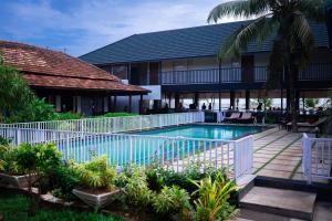 a swimming pool in front of a resort at West Bay Palm Tree Beach Resort in Varkala