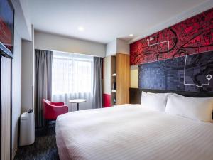 a hotel room with a bed and a red wall at ibis Osaka Umeda in Osaka