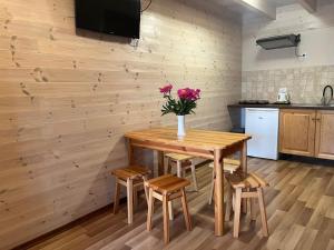 a kitchen with a wooden table with chairs and a vase of flowers at Domki Vesper Międzywodzie in Międzywodzie +18 photos