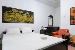 a bedroom with a white bed and an orange chair at Hotel Srikandi Semarang RedPartner in Candi +89 photos