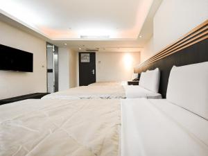 a hotel room with two beds and a flat screen tv at Guide Hotel Taoyuan Fuxing in Taoyuan