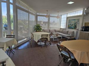 a living room with tables and a couch and windows at Tortugas B&B in Giarre