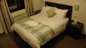 a bed with a green and white blanket and pillows at Bay Lodge in Birchington