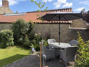 a table and chairs under an umbrella in a garden at 2 Bed in York oc-96097 in Helmsley