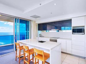 a kitchen with a white counter and some chairs at Luxurious 2 Bedroom Apartment - Ocean View in Gold Coast
