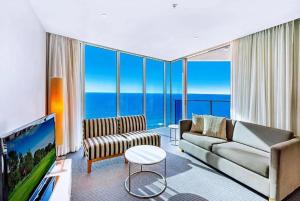 a living room with a couch and a flat screen tv at Luxurious 2 Bedroom Apartment - Ocean View in Gold Coast