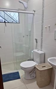 a bathroom with a toilet and a glass shower at Suíte Completa in Barra Velha