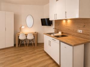 a kitchen with white cabinets and a table and chairs at Aparthotel Fuenlabrada Central in Fuenlabrada