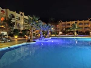 a large swimming pool with palm trees in front of a building at Casa Dòdò - Sunny Lakes Compound in Sharm El Sheikh