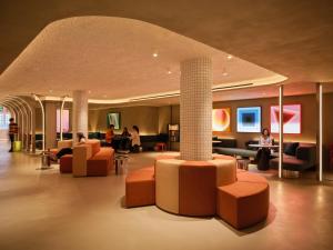 a hotel lobby with couches and chairs and a column at Otherwander Soho Pod Hotel in London