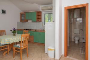 a kitchen with green cabinets and a table and chairs at Apartments Laguna 2 in Bol +130 photos