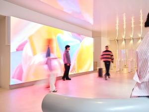 a group of people walking through a museum with a large screen at Otherwander Soho Pod Hotel in London