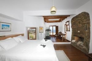 a bedroom with a white bed and a stone fireplace at ⋆ 5BR Oceanside View Near Lighthouse- Pharos VM ⋆ in Mikonos