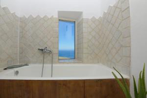 a bath tub with a window in a bathroom at ⋆ 5BR Oceanside View Near Lighthouse- Pharos VM ⋆ in Mikonos +46 photos