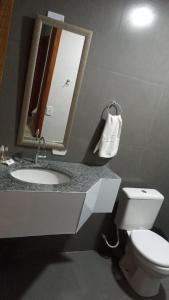 a bathroom with a sink and a toilet and a mirror at Pousada Casa Terra de Pinheiros in Santo Antônio do Pinhal