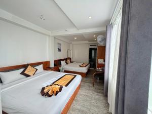 a hotel room with two beds and a living room at Cherry Luxury Hotel in Da Lat