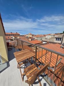 a balcony with a wooden table and chairs on a roof at Apartmaji Sonce in Piran