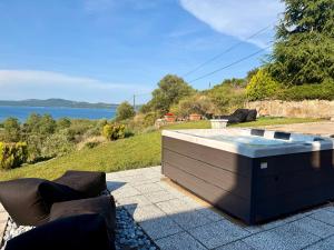 a hot tub on a patio with a view of the water at STONEHOUSE & CASA AL SOLE e AL MARE in Nea Roda