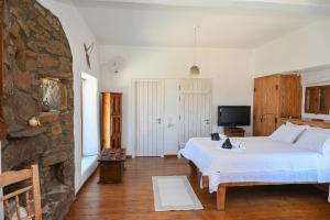 a bedroom with a white bed and a stone wall at ⋆ 5BR Oceanside View Near Lighthouse- Pharos VM ⋆ in Mikonos