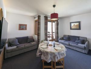 a living room with a table and two couches at Le Nid Rouge Risoul Balcony & View Ski 100 m in Risoul