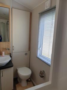 a bathroom with a toilet and a sink and a window at K7 Annandale in Winthorpe