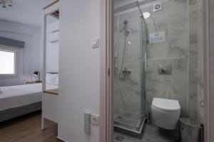 a bathroom with a shower and a toilet and a bed at SLV Irida Apartment in Ofrínion