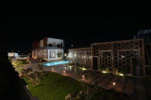 a building with a swimming pool at night at Sandy Resort in Agastīswaram