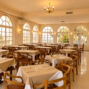 a dining room with tables and chairs and windows at Hôtel Archipel in Monastir