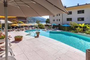 a swimming pool with an umbrella and chairs and a building at Ambienthotel Spiaggia in Malcesine