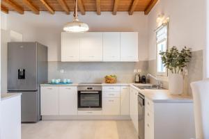 a white kitchen with white cabinets and a refrigerator at Villa Sun Sky in Aggelika