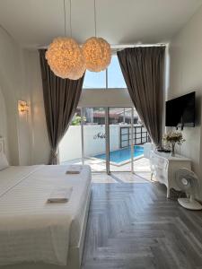 a bedroom with a bed and a tv and a large window at Nadda Pool Villa Ranong in Ban Bang Rin (1)