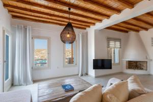 a living room with a couch and a tv and windows at Villa Sun Sky in Aggelika