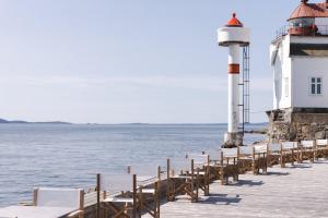 a row of chairs on a pier with a lighthouse at Vilma Sjøbad in Filtvet