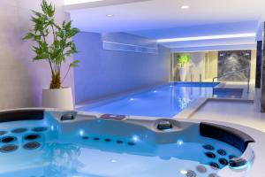 a large swimming pool with a blue tub in a room at Hotel Rubin DHS in Kruševac