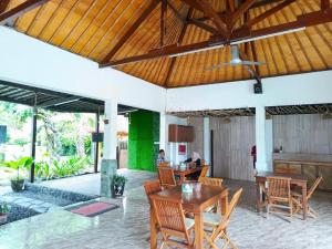a patio with wooden tables and chairs in a house at Melati resort kuta lombok in Kuta Lombok