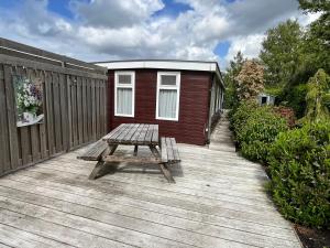 a wooden deck with a picnic table and a building at Houseboat Linquenda in Woubrugge