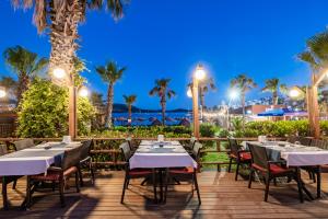 ein Restaurant mit Tischen, Stühlen und Palmen in der Unterkunft Costa Bitezhan Beach Hotel in Bitez