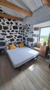 a bed in a room with a stone wall at Adega do capitao in Piedade