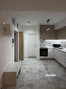 a kitchen with white cabinets and a large tile floor at Skopje Riverfront Modern Apartment in Skopje